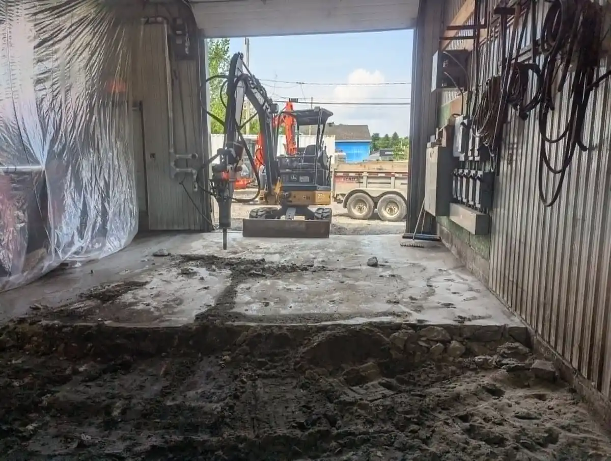 Mini-excavatrice avec marteau hydraulique pour la démolition d’une dalle de béton à l’intérieur d’un bâtiment