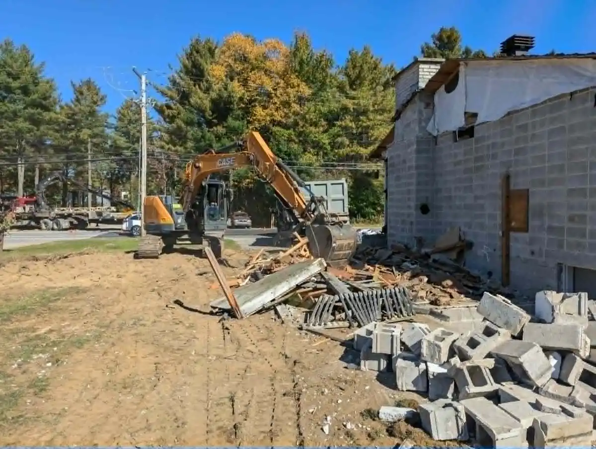 Excavatrice effectuant la démolition d’une structure extérieure en maçonnerie