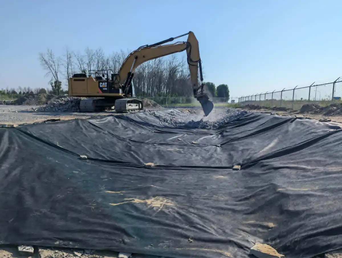 Excavatrice travaillant dans un bassin recouvert de géotextile