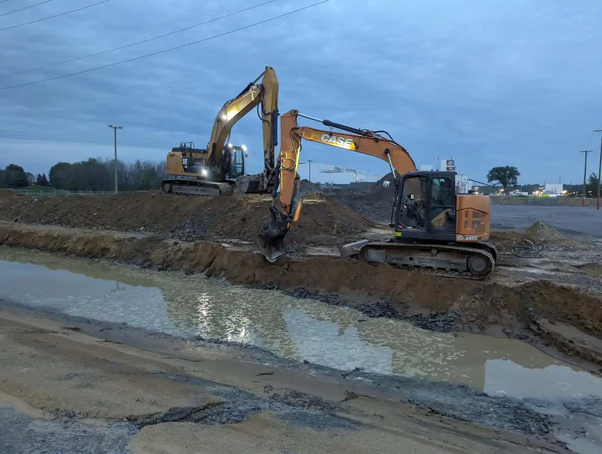 Deux excavatrices en opération sur un chantier boueux avec accumulation d’eau